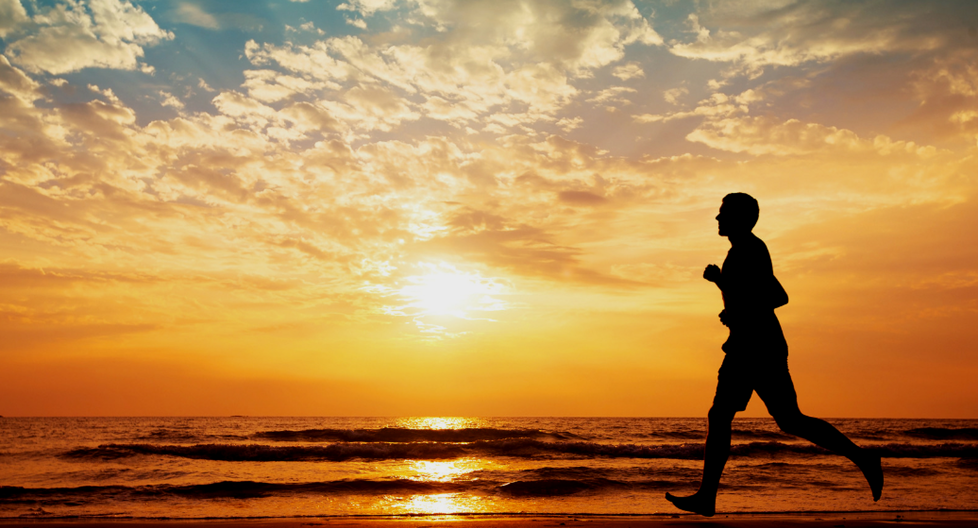 Person running on beach at sunset